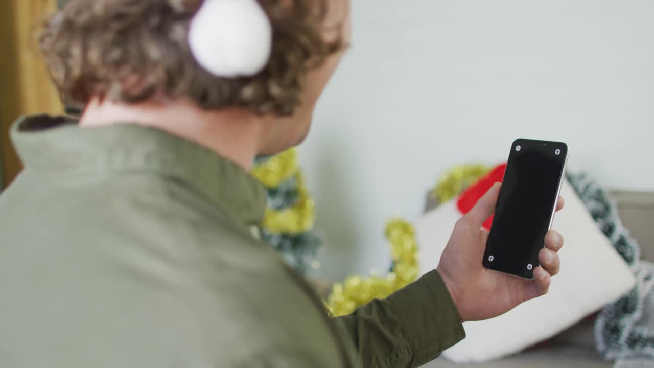 크리스마스에 스마트폰을 사용하는 산타 모자를 입은 행복한 백인 남자