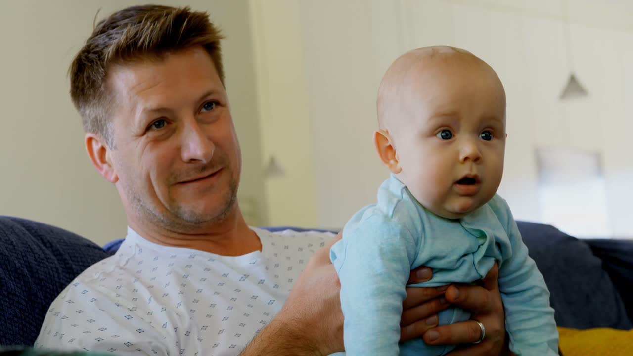padre y bebé viendo televisión en la sala de estar 4k