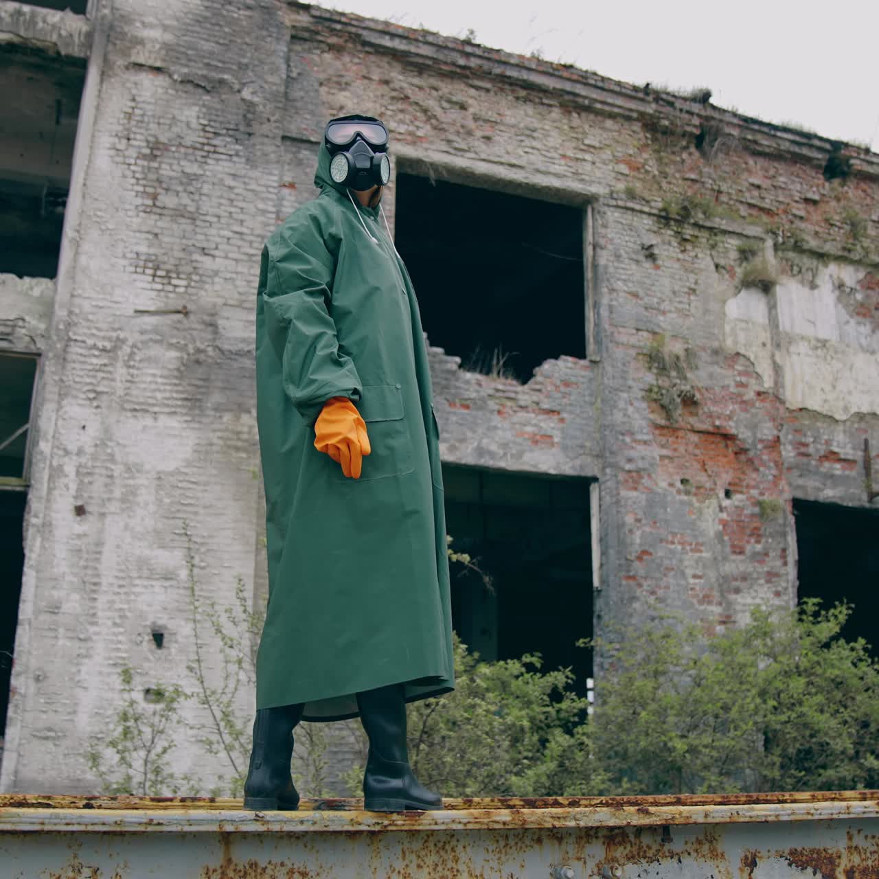 Man in special radioactive uniform walking down. Man wearing green chemical suit and gas mask