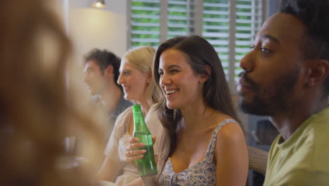 multi-cultural group of friends enjoying beer and takeaway food at home together