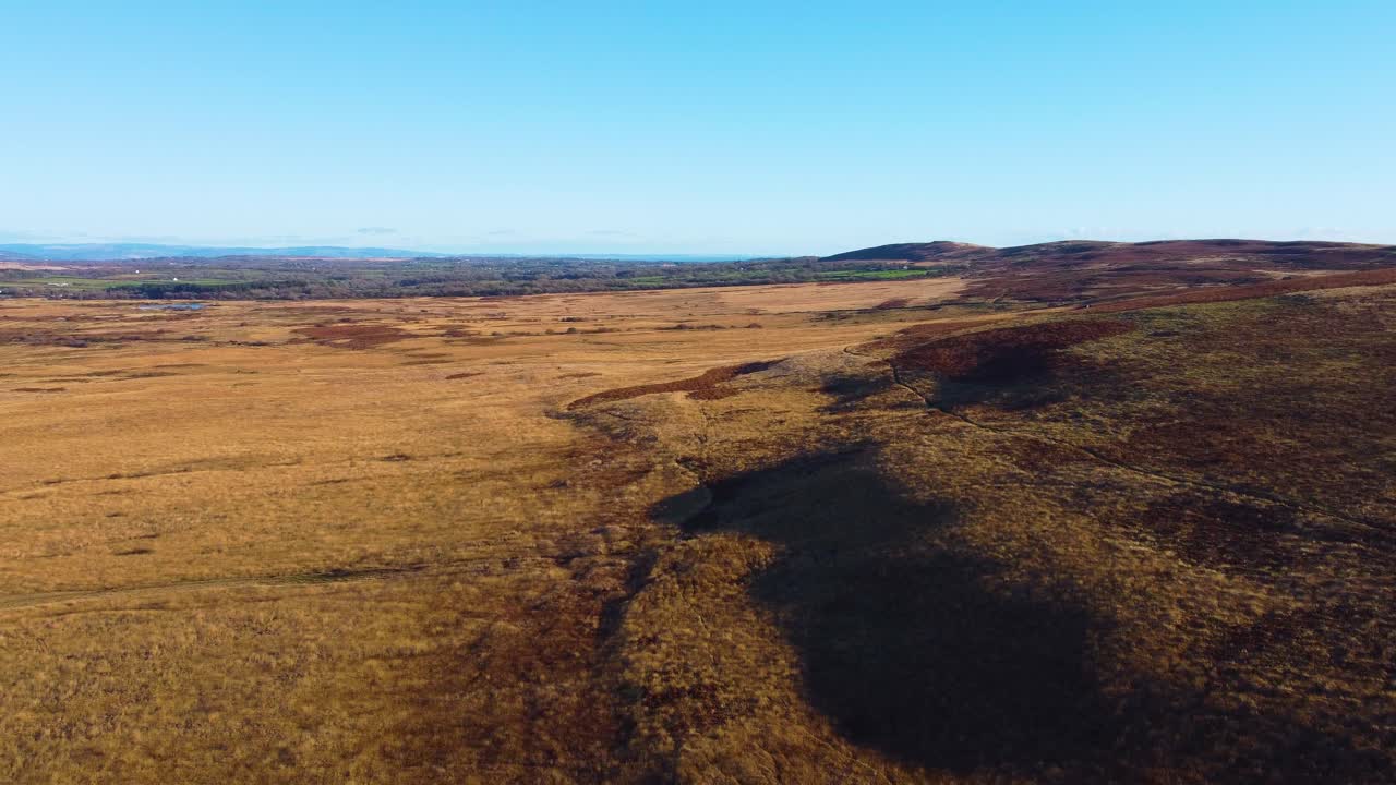 Dronebillede, der bevæger sig sidelæns over Gower i South Wales med udsigt over landskabet, der strækker sig langt ud i det fjerne. Smukt, naturskønt landskab.