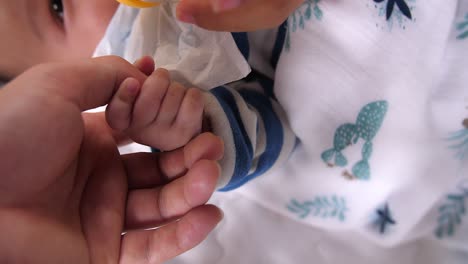 baby holding mother's finger while drinking milk from a bottle, video in 4k