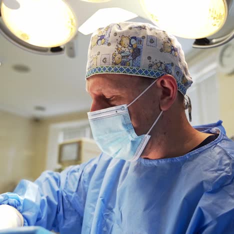 male surgeon in a funny cap with teddy bears and surgical mask. doctor working at surgery. view from below