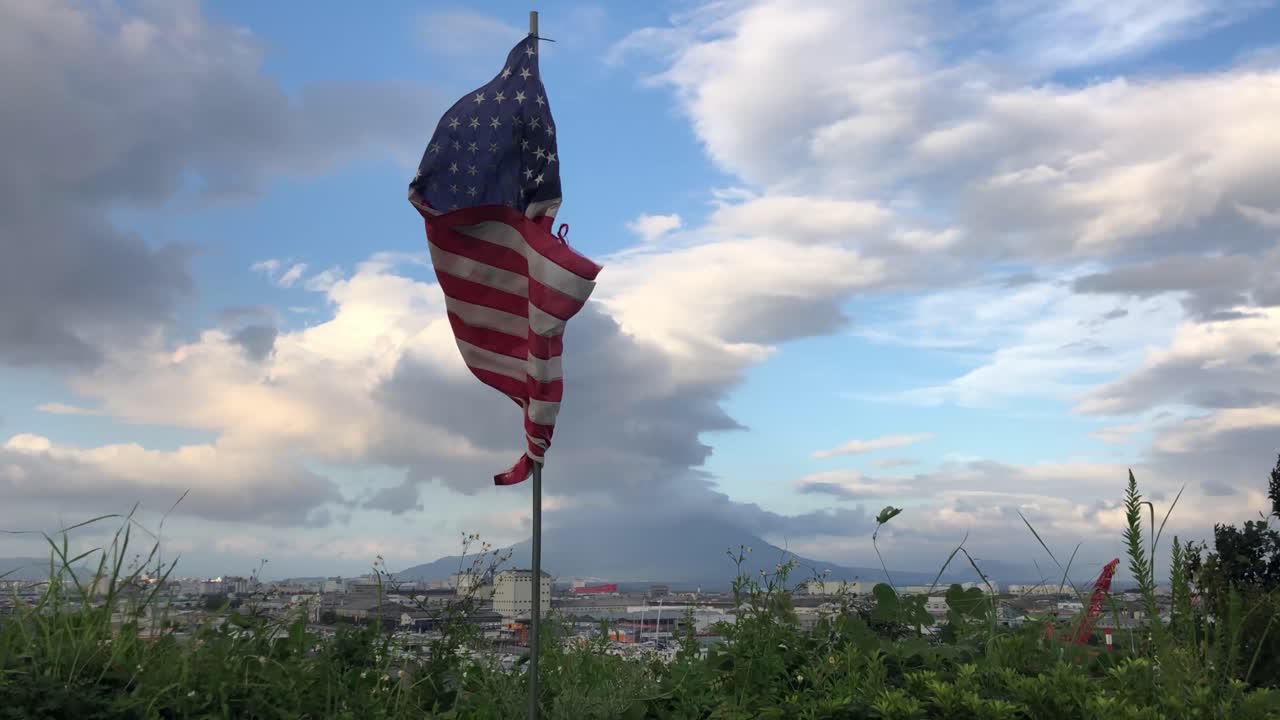 Bandiera americana che sventola al vento a mezzogiorno sullo skyline del Giappone