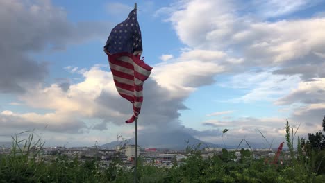 american flag blowing in the wind at noon against japan skyline