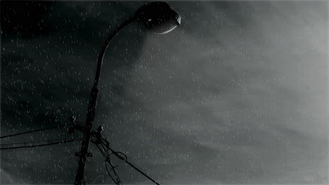 an ominous atmosphere where the street light illuminates the falling rain against a dark overcast sky