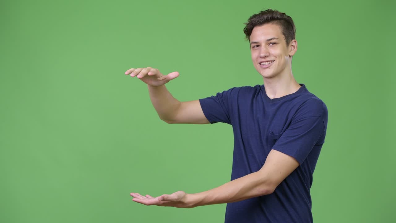 Young handsome teenage boy showing something