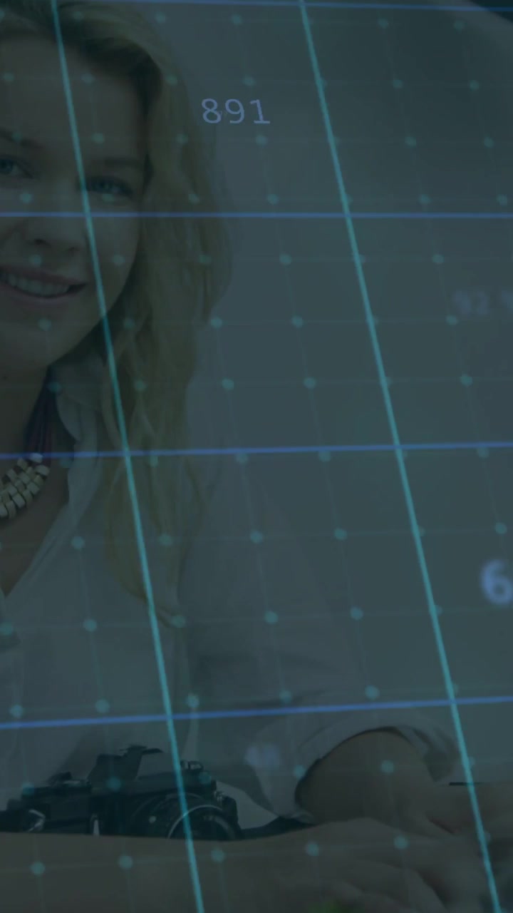 Video vertical: Mujer en un escritorio tocando el trackpad, activando una cuadrícula de datos en movimiento y analizando finanzas.
