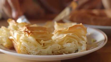 close-up of hands cutting a flaky pastry