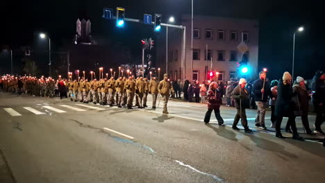lāčplēsis day torchlight procession crossing a city street at night in jelgava, latvia