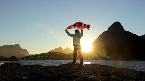 woman waving the flag of norway at sunset