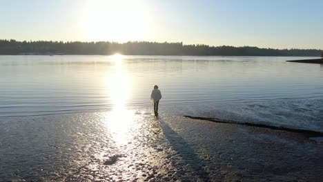 Low-level-aerial-drone-flight-around-woman-at-sunset-on-the-Puget-Sound-near-Olympia-in-Washington-State