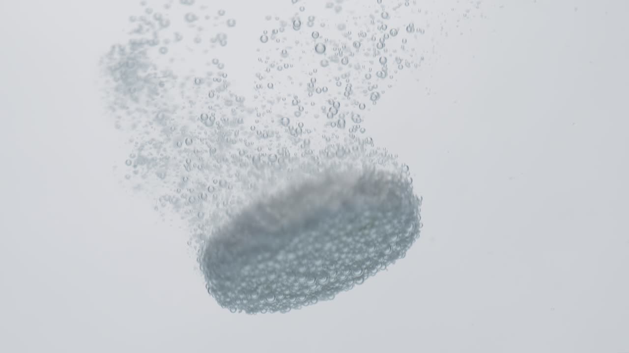 Extreme Close-up effervescent tablet, pill bubbling underwater. Shot on super slow motion camera 1000 fps