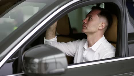 man sitting inside vehicle in car dealership