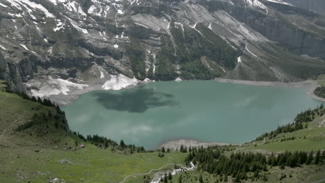 cloud draws black shadow on the light blue water of the oeschinensee in the swiss alps