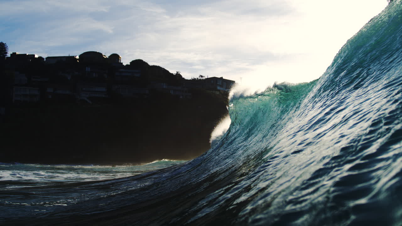 Sunset glint hits clean crest of wave as it rolls shoreward in abstract slow motion