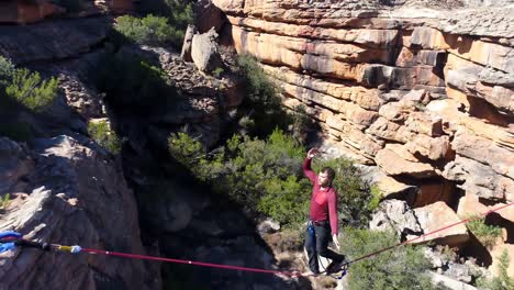 male highliner walkng on a rope over rocky mountains 4k