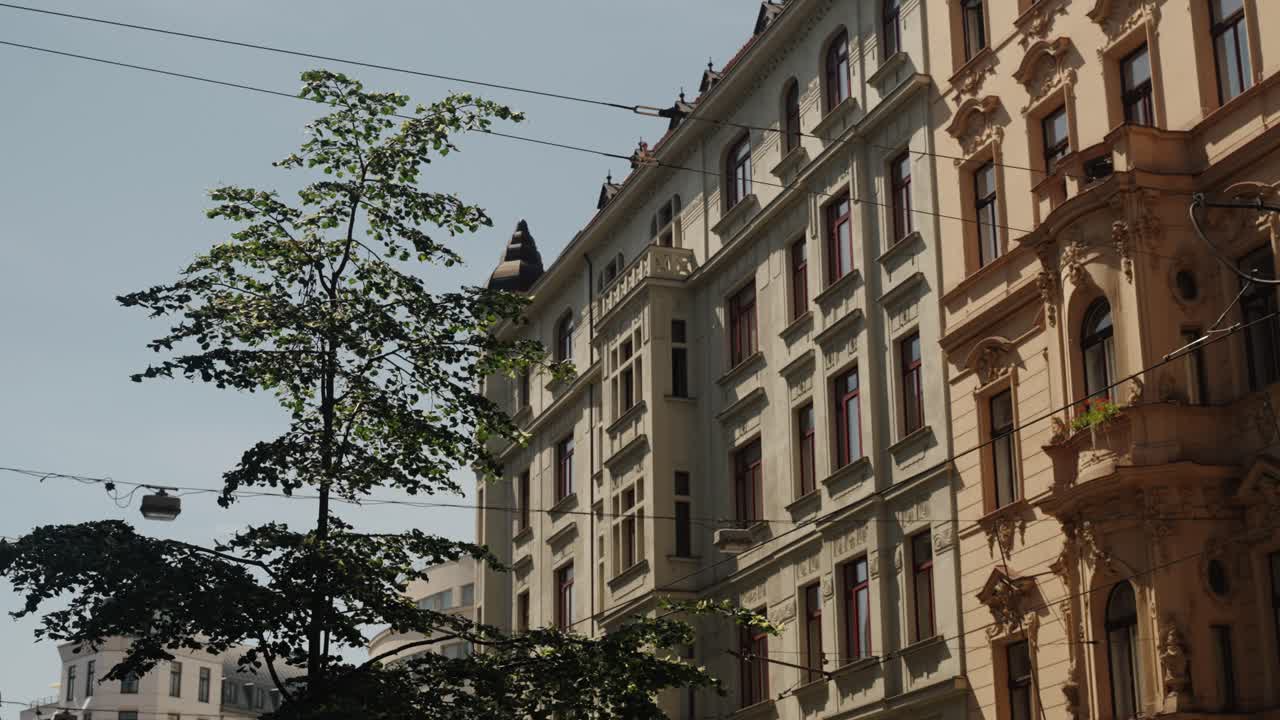 Historic Prague street with ornate buildings and tram cables under summer light