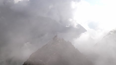 aerial clip of a mountain peak with clouds rolling over it in langtang valley, nepal