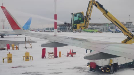 Enteisung-Des-Flugzeugs-Vor-Dem-Flug.-Anti-Icing-Ist-Die-Anwendung-Von-Chemikalien,-Die-Nicht-Nur-Enteisen,-Sondern-Auch-Auf-Einer-Oberfläche-Verbleiben-Und-Die-Neubildung-Von-Eis-Weiter-Verzögern