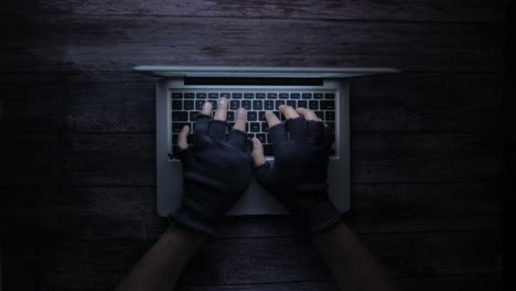 manos con guantes escribiendo en la computadora portátil por la noche