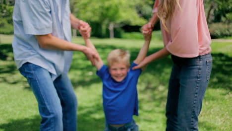 boy being swung back and forth by his parents who are holding his arms