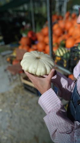 person holding a white decorative squash at a pumpkin patch