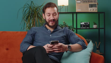 lebanese young man sitting on sofa using smartphone share messages on social media application