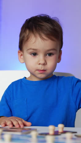 caucasian baby boy playing with his toys at desk. kid finishes a game and stands up and leaves. vertical video
