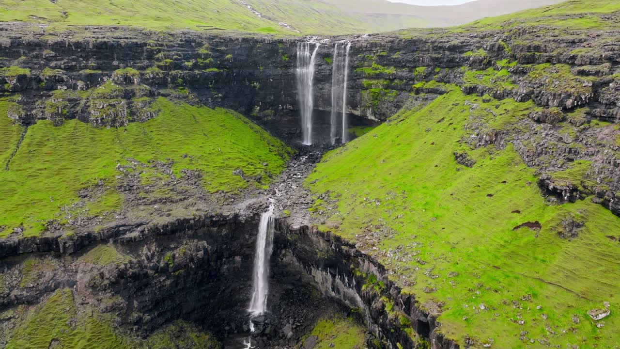 una impresionante cascada que fluye a través de acantilados verdes en las islas feroe
