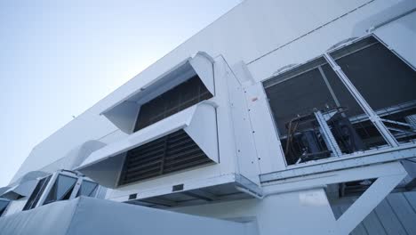 large ventilation pipes on facade of commercial building. outdoor split air conditioner units mounted on industrial building facade. air conditioning system assembled on side of building