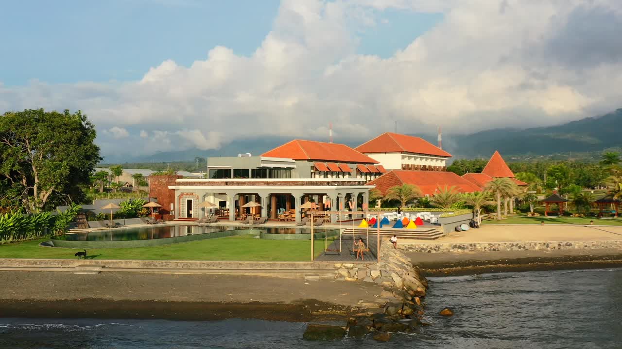 황금시간대 일몰 동안 로비나 발리의 해변 휴양지에서 그네에서 휴식을 취하는 어린 소녀의 공중