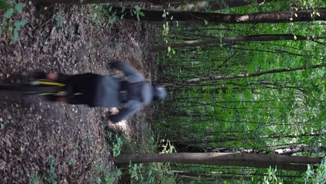 Vertical-shot-from-behind-of-man-jumping-on-electric-bike-in-the-forest-doing-tricks-in-slow-motion