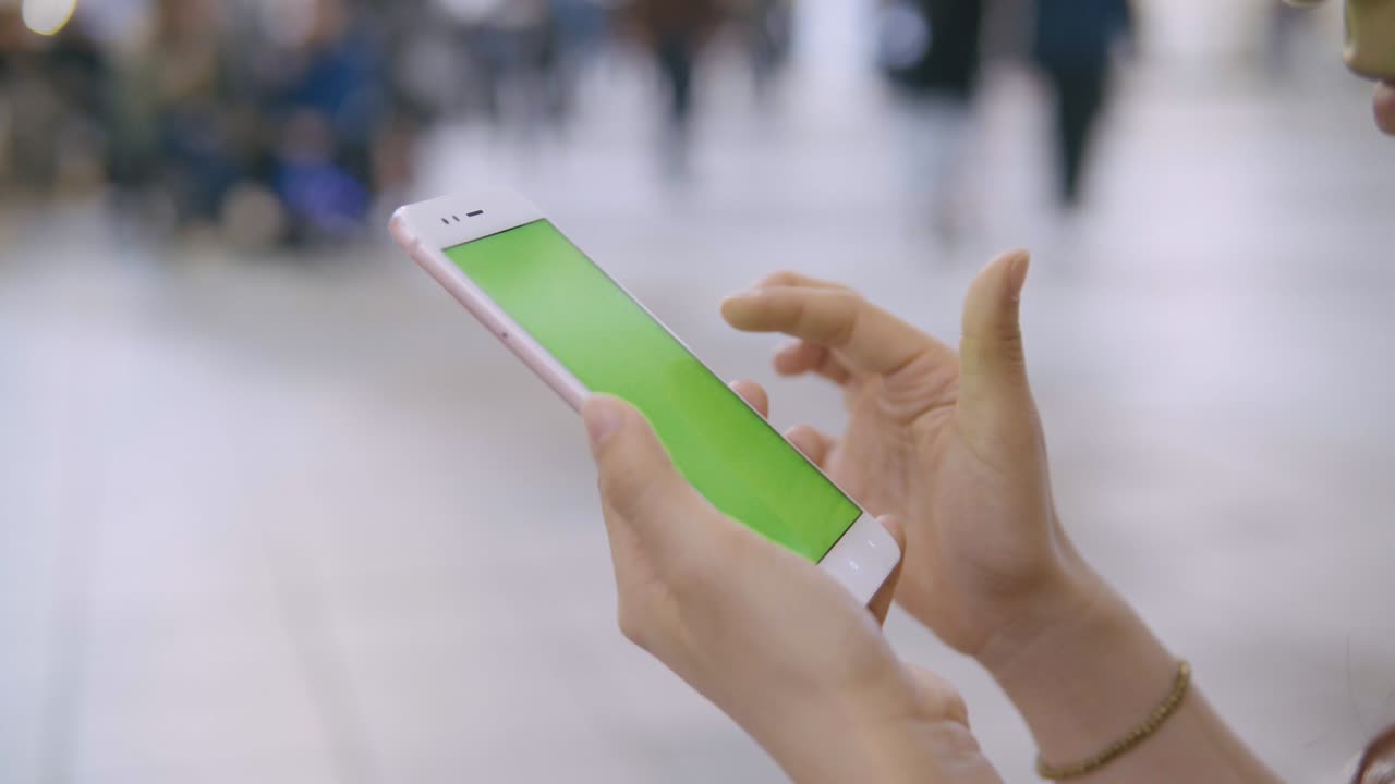 거리에서 초록색 화면의 스마트폰을 사용하는 여성.