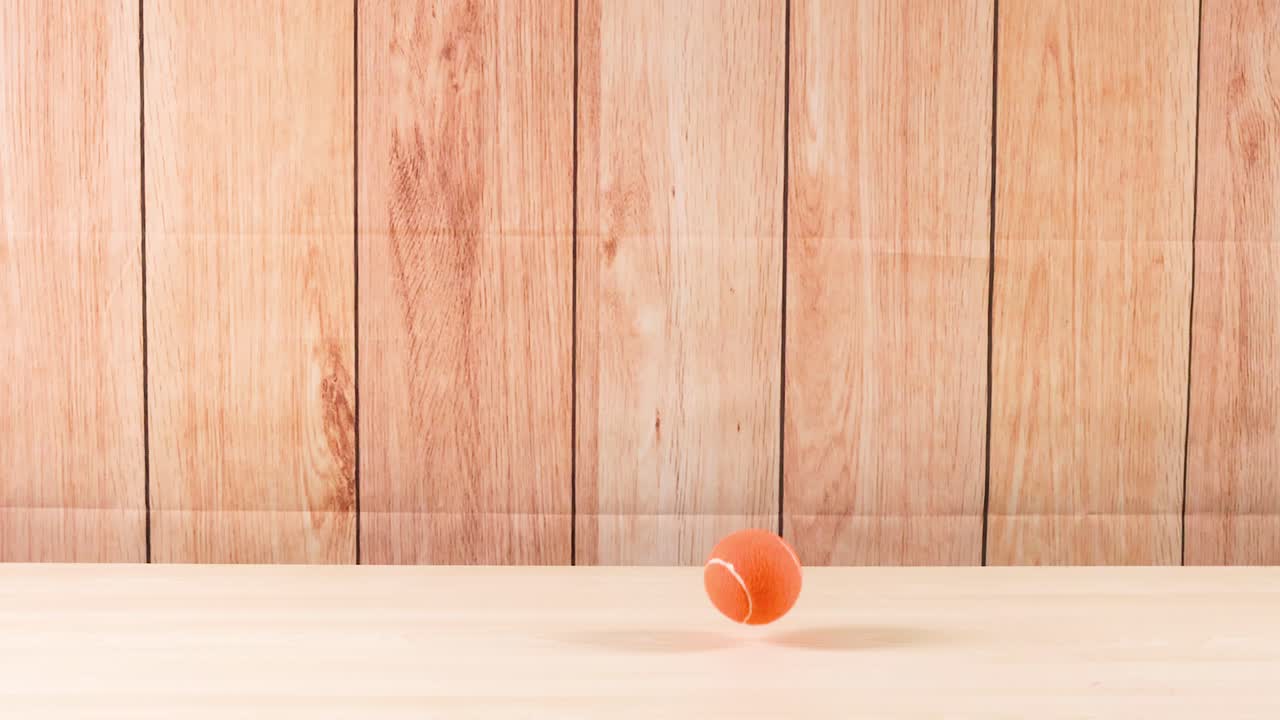 una pelota de tenis rebota en un piso de madera