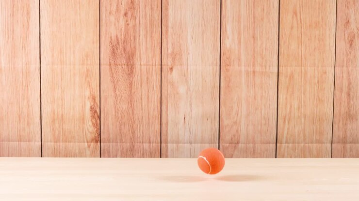 A tennis ball bounces on a wooden floor
