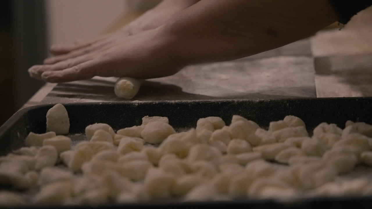 Mani che stendono l'impasto per fare gnocchi fatti in casa