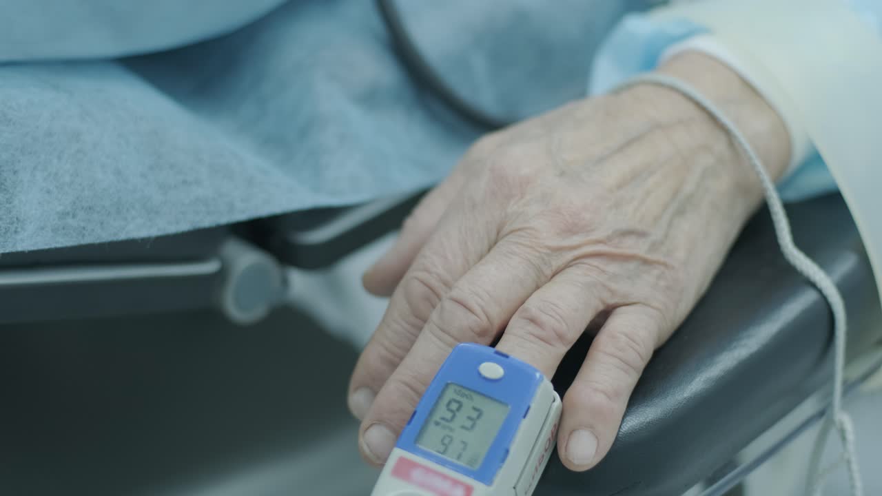 Old patient with pulse oximeter on finger for monitoring during surgery in hospital