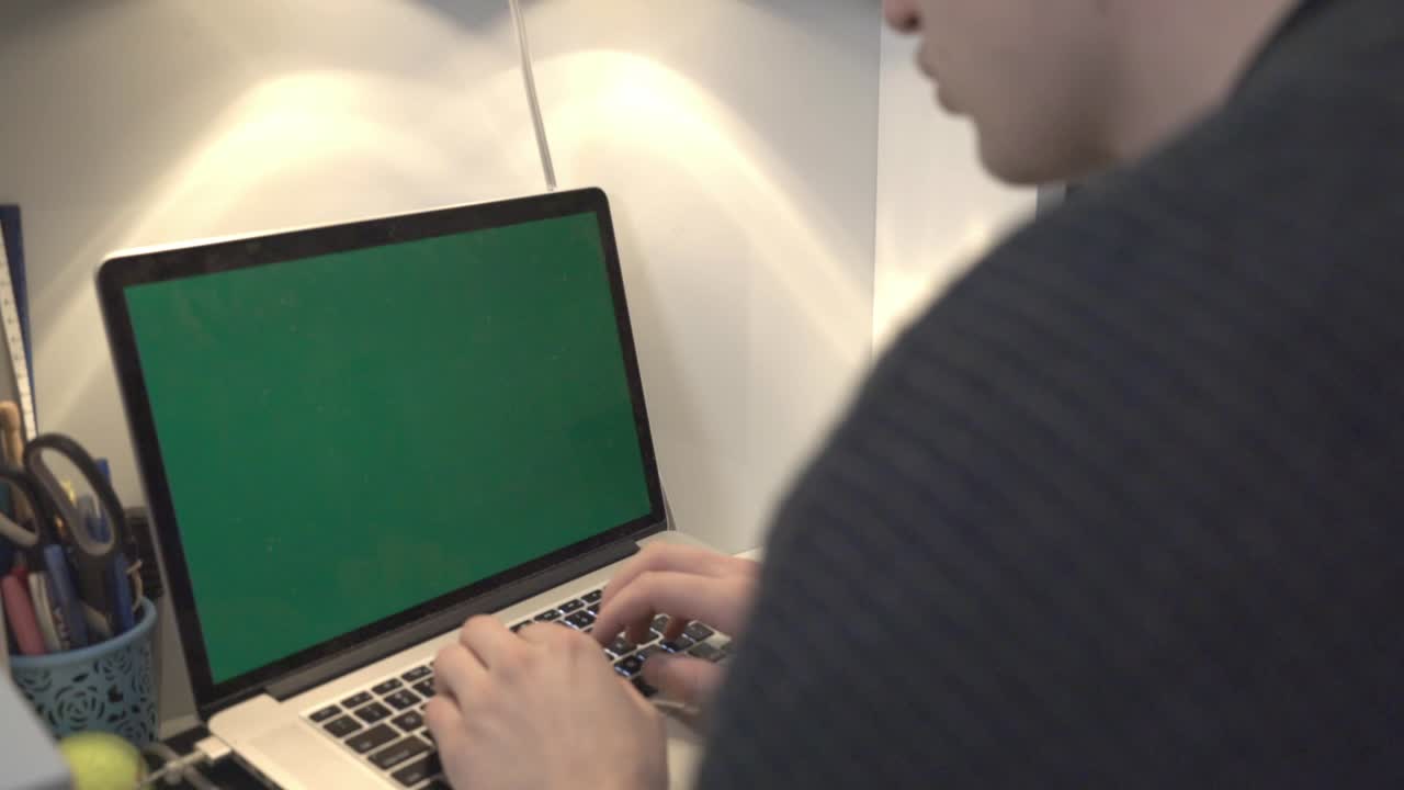A Young Man Working On Its Laptop With Green Screen Inside The Office.- closeup shot