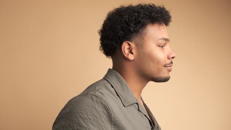 happy young man smiling at camera in beige studio