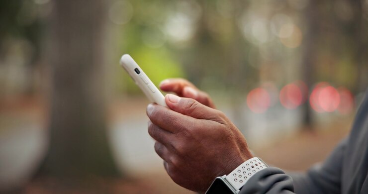 Person Using Smartphone Outdoors with Smartwatch on Wrist