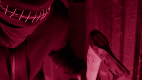 close up view of an expectant man wearing black balaclava and holding an ax hidden in a ruined building 1