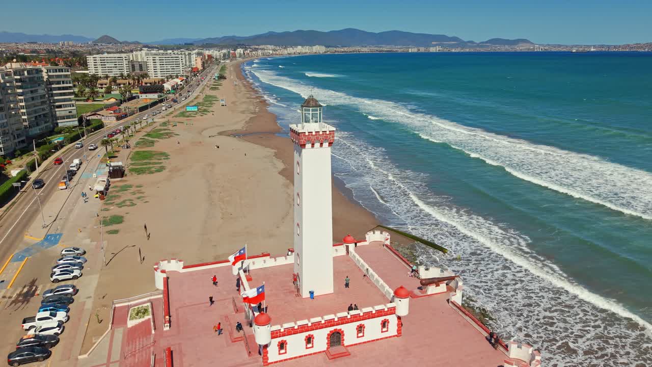 Aerial view of Faro de La Serena lighthouse beside the ocean, beach, and urban coastline