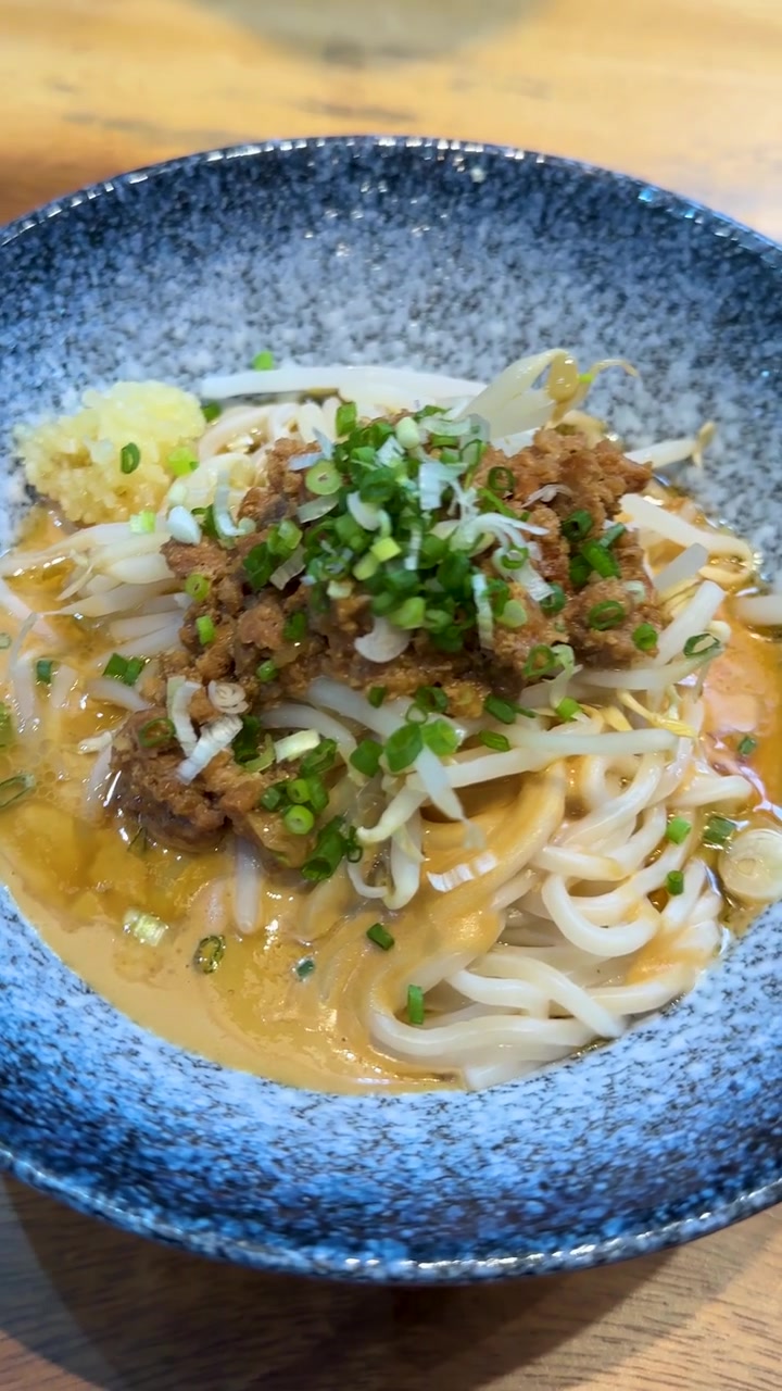 陶器の丼に盛られた、豚ひき肉、もやし、ネギが乗った伝統的な台湾麺のクローズアップ。