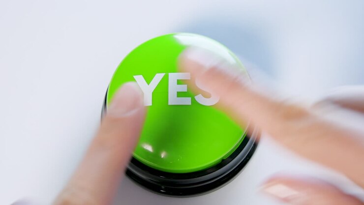 Giovane donna che preme un pulsante verde 'Sì'. Concetto di accordo, consenso, approvazione, accettazione, attivazione. Premere un vero pulsante dell'interfaccia. Votare, scegliere qualcosa di buono. Decisione positiva, recensione, feedback