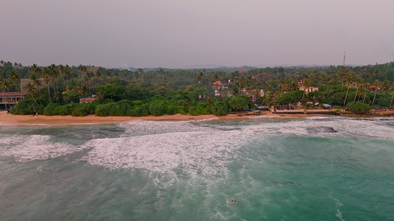 Stunning aerial footage capturing the breathtaking Weligama coastline bathed in the warm, golden hues of sunset.