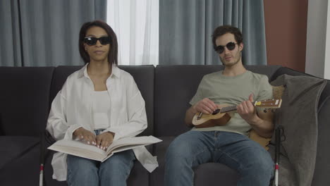 Front-view-of-blind-friends-sitting-on-a-sofa-in-a-flat