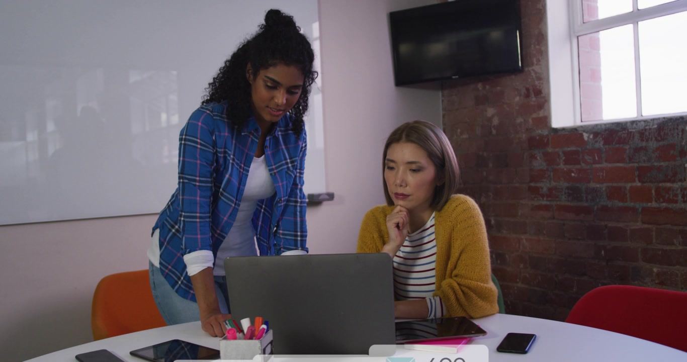 Two coworkers checking marketing metrics on laptop as coworker tapping pad generating overlays
