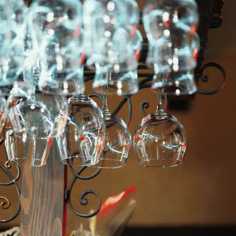 clean wine glasses hanging upside down above a bar rack in restaurant. bartender wipes glasses sqare video