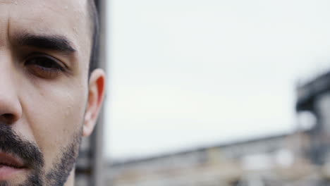 retrato de media cara de la cara sudorosa del boxeador masculino durante un entrenamiento al aire libre en una fábrica abandonada en una mañana nublada